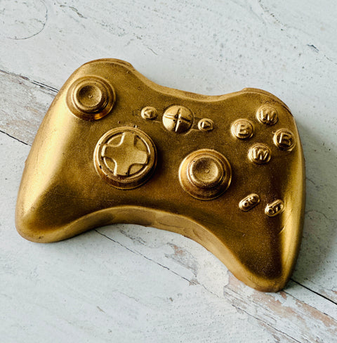 a close up of a gold controller on a wooden surface